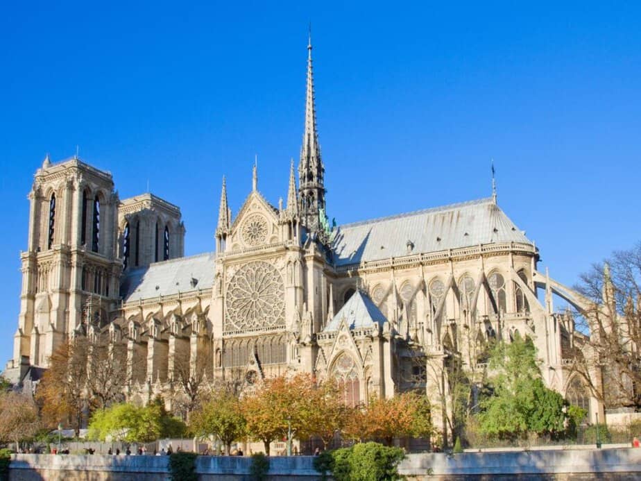 Notre-Dame Cathedral in Paris, viewed from the Seine River, displaying its Gothic architecture with the intricate facade and flying buttresses