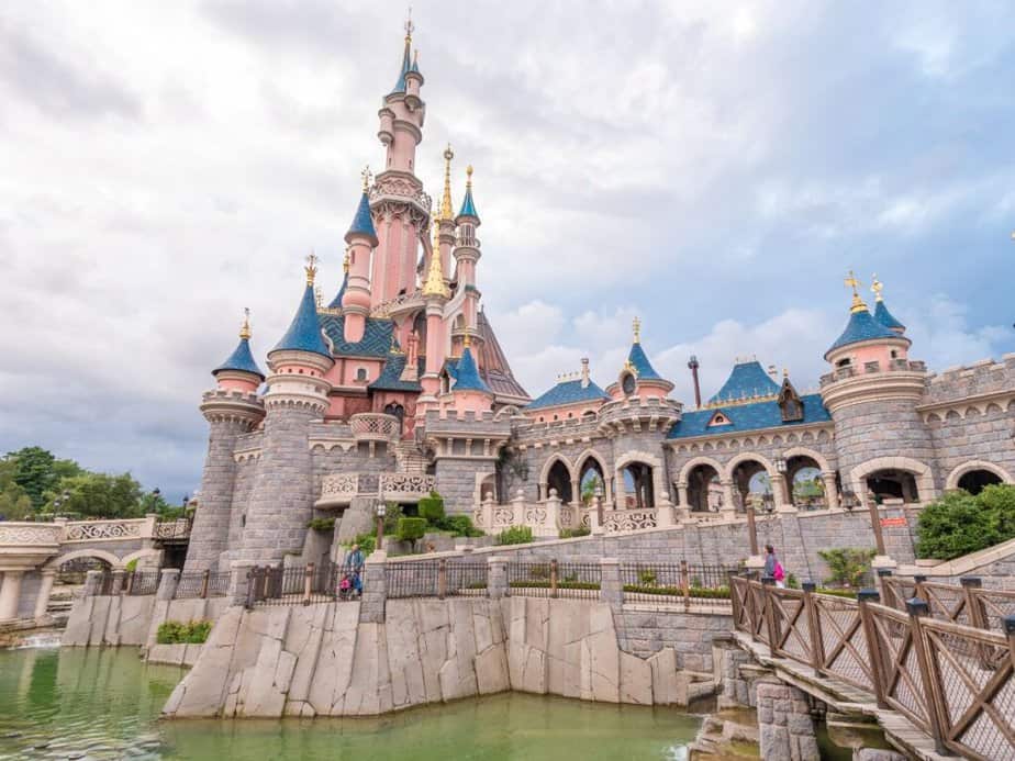 Sleeping Beauty's Castle at Disneyland Paris, with its iconic pink and blue turrets against a cloudy sky, a fairytale addition to any Paris bucket list.