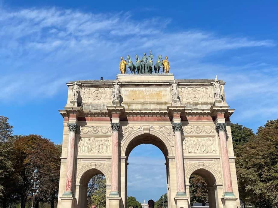 The Arc de Triomphe du Carrousel in Paris, showcasing its detailed sculptures and bas-reliefs under a clear blue sky, a perfect representation of Parisian historical architecture for a Paris bucket list.