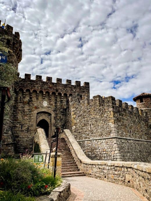 Stone steps leading up to the medieval-style Castello di Amorosa winery in Napa Valley, with its turreted walls and a dramatic sky overhead, a unique blend of history and viticulture to explore in January.