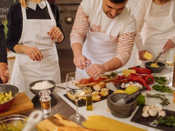 A group of people in aprons engaged in a cooking class, preparing fresh ingredients for a meal, a warm indoor activity to enjoy in Napa Valley in January.