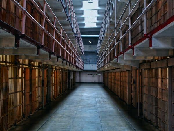 The eerie and historic cellblock of Alcatraz Island prison, with rows of closed cell doors and barren corridors, a thought-provoking sight that questions if the Alcatraz tour is worth it.